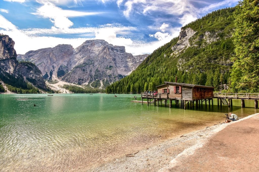 Scorcio del lago di Baies con il tipico pontile, la casetta delle barche e lo sfondo tra montagne verdi e montagne di roccia