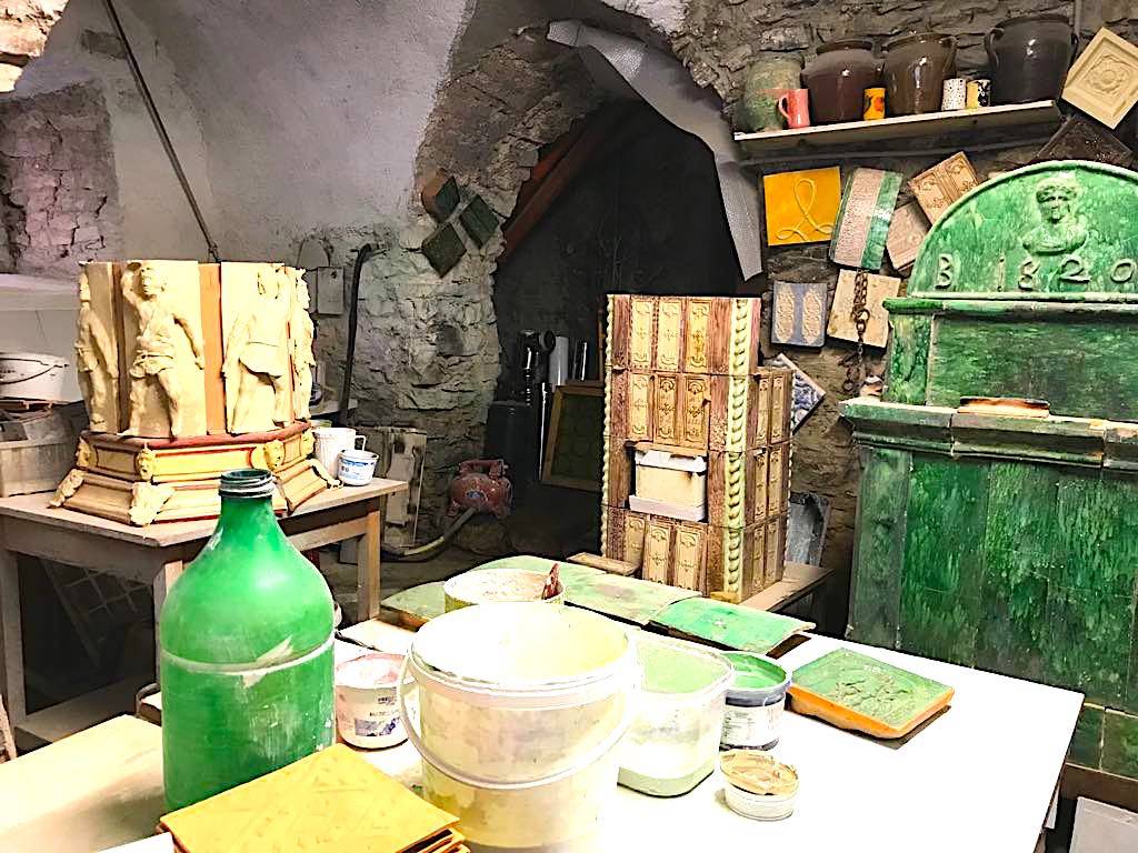 Laboratorio del maestro fornelaro Ferruccio Marinelli-tavolo e colori-Stufe a olle in Val di Non